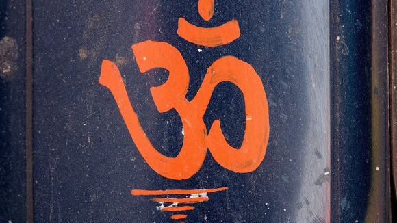 Das Wort Om geschrieben in Sanskrit auf blauem Untergrund.
