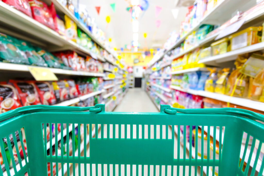 Fotoausschnitt zeigt den Blick vom Einkaufswagen in einen Supermarktgang.